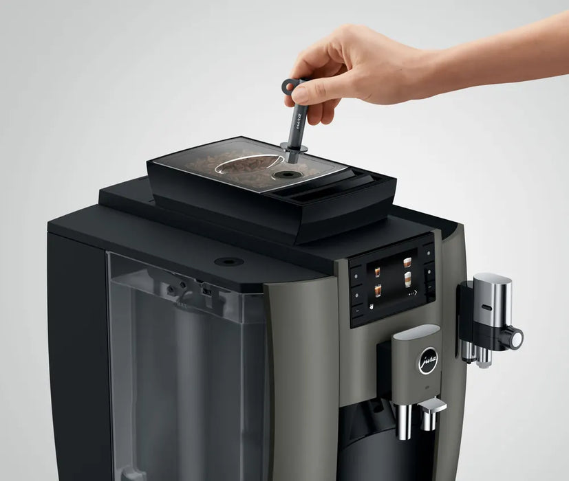 JURA W8 Dark Inox met bonenreservoir en bedieningspaneel, hand voegt koffiebonen toe