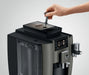 JURA W8 Dark Inox met bonenreservoir en bedieningspaneel, hand voegt koffiebonen toe