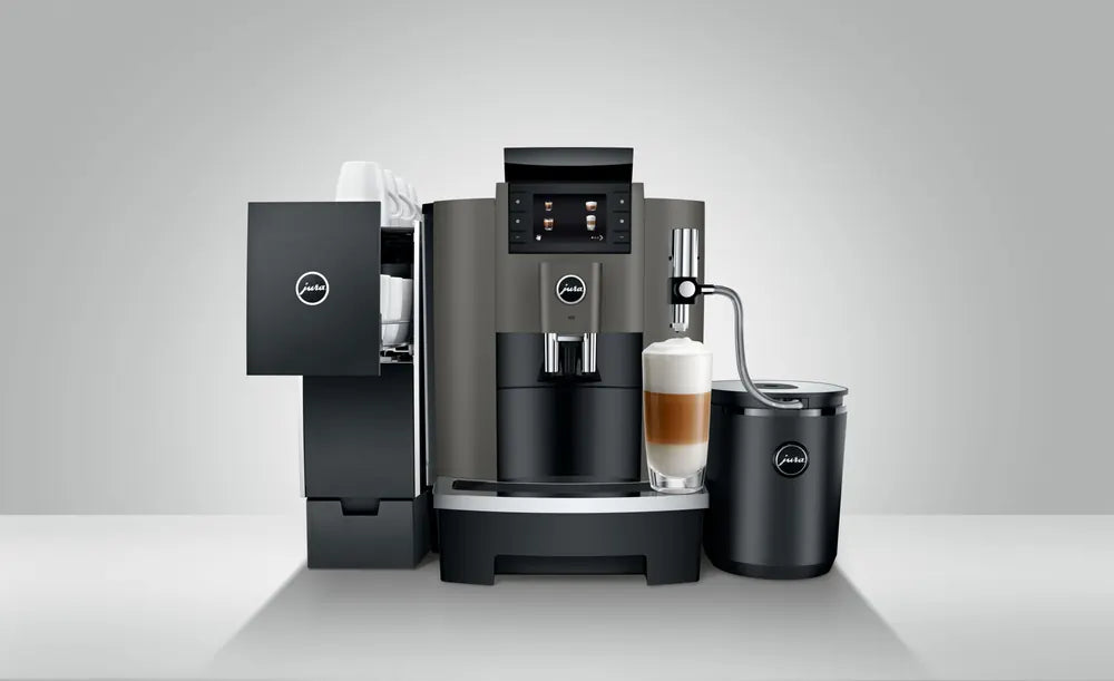 JURA W8 Dark Inox espressomachine met melkopschuimer en kopje latte macchiato op een grijze achtergrond