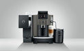 JURA W8 Dark Inox espressomachine met melkopschuimer en kopje latte macchiato op een grijze achtergrond