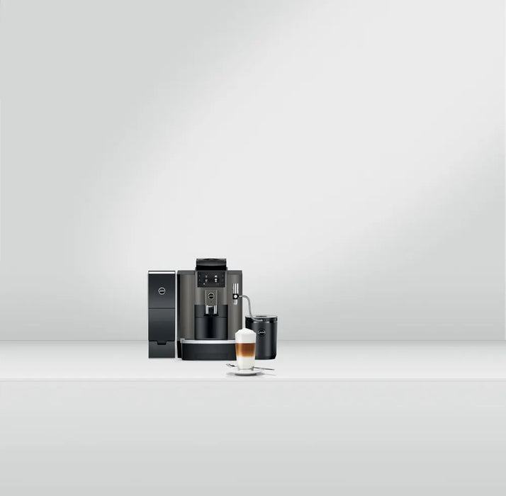 JURA W8 Dark Inox zakelijke koffiemachine met melkopschuimer en kopje latte macchiato op witte achtergrond