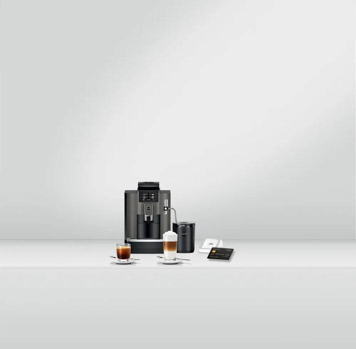 JURA W8 Dark Inox zakelijke koffiemachine met kopjes koffie en melkschuimer op een witte achtergrond