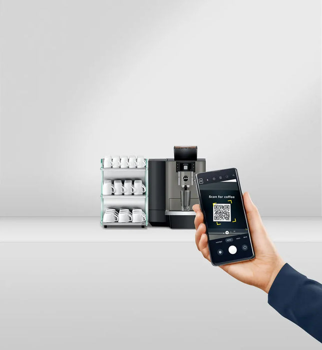 JURA X10 Dark Inox zakelijke koffiemachine met smartphonebediening en kopjesrek op de achtergrond