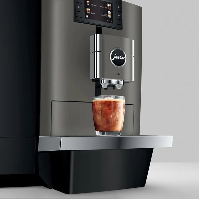 JURA X10c Dark Inox koffiemachine met glas ijskoffie op zilveren lekbak