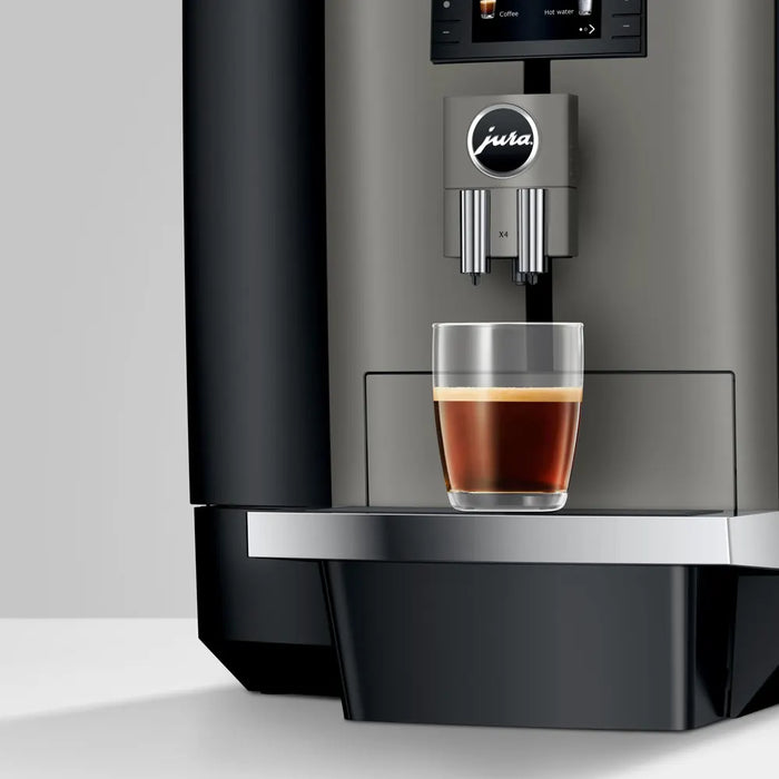 JURA X4 Dark Inox zakelijke koffiemachine met glazen kopje espresso op de zilverkleurige lekbak