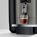 JURA X4 Dark Inox zakelijke koffiemachine met glazen kopje espresso op de zilverkleurige lekbak