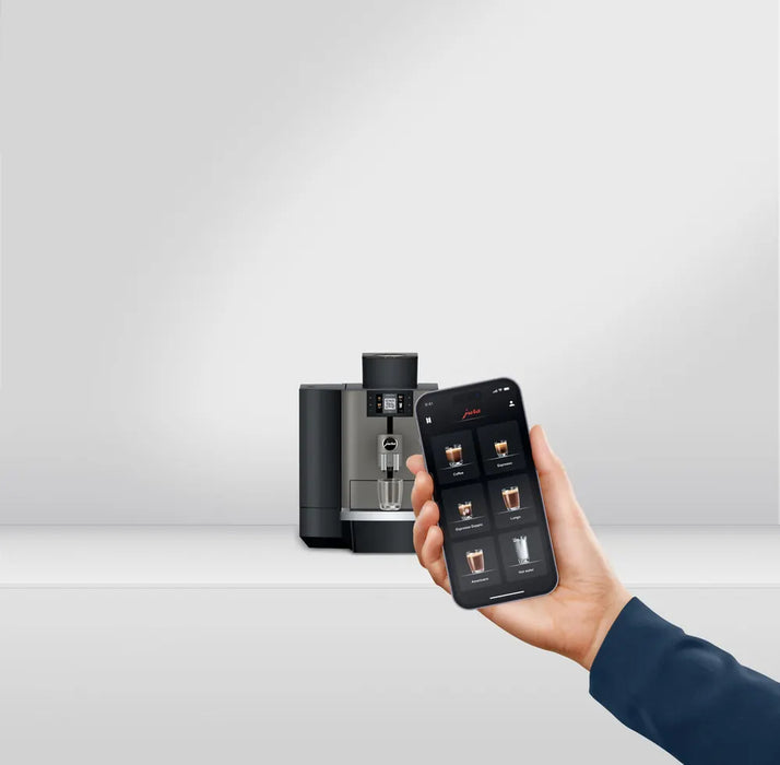 JURA X4 Dark Inox zakelijke koffiemachine met smartphonebediening in een moderne omgeving