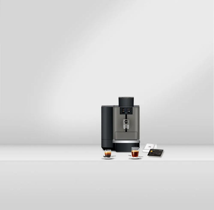 JURA X4 Dark Inox zakelijke koffiemachine met display en twee kopjes espresso op een witte ondergrond