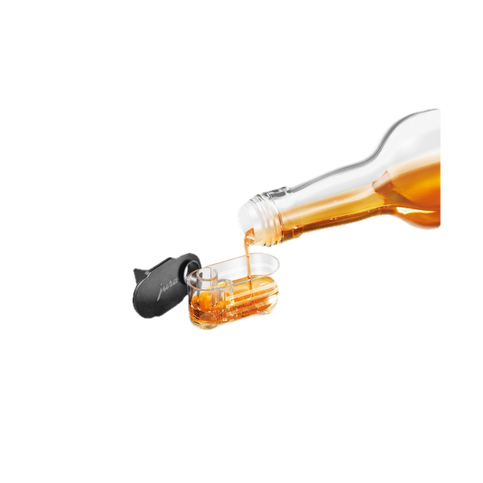 JURA Siroopopzetstuk set van 2 met zwart siliconen dopje, goudgele siroop stroomt in glas | Arte dell' espressO